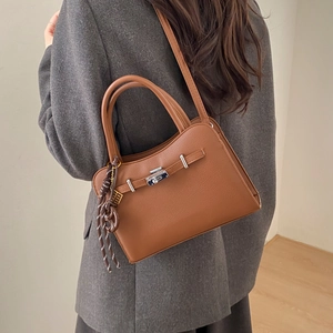 Detail of a brown lychee pattern leather handbag with silver clasp on a female model