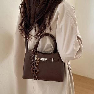 Detail of dark brown leather tote featuring silver buckle and stylish bag charms
