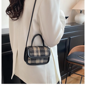 Detail of vintage plaid tweed flap handbag with black leather trim on a model in a blazer