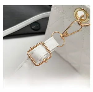 Détail de la bandoulière réglable avec boucles dorées sur le sac à main matelassé blanc