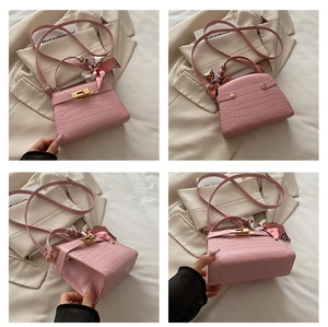 Detailed views of pink crocodile embossed handbag with gold lock and silk scarf decor