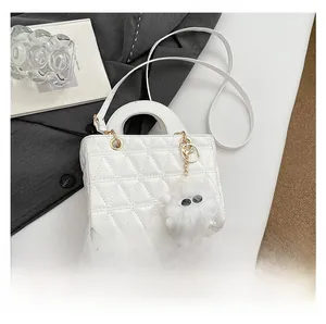 Détail d'un sac à main en cuir matelassé blanc avec ferrures dorées et breloque peluche