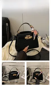 Detail of black crocodile pattern handbag featuring decorative floral silk scarf and gold lock