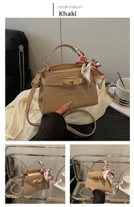 Detail of khaki crocodile pattern handbag with printed silk scarf on handle and gold clasp