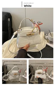 Detailed view of a white crocodile pattern square bag with decorative silk scarf handle