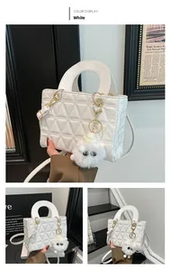 Gros plan du sac blanc matelassé en triangle avec un charmant pendentif d'œil en peluche