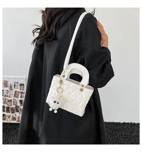 Vue arrière d'un sac à main matelassé blanc avec bandoulière et pendentif peluche sur un modèle