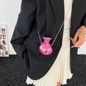 Chic rose pink metallic money bag clutch with gold chain strap worn on black blazer
