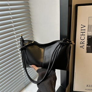 Minimalist black leather tote bag with knotted handle and gold metal hardware