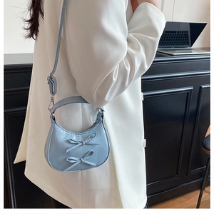 Nahaufnahme einer hellblauen Halbmond-Schultertasche mit eleganten Schleifen aus PU-Leder