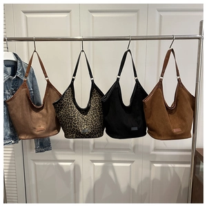 Detail view of large tote bags in leopard print and suede textures on a clothes hanger
