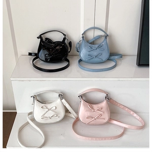 Close-up of colorful mini crossbody bags with bow details and glossy patent finish