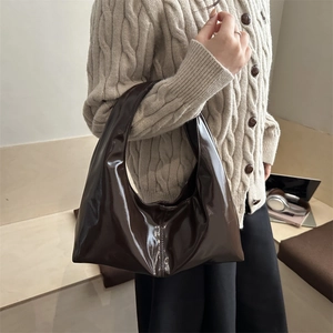 Minimalist glossy dark brown hobo shoulder bag shown on shoulder over knit sweater