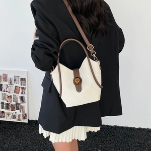 Borsa tote beige con finiture in pelle marrone e chiusura metallica indossata