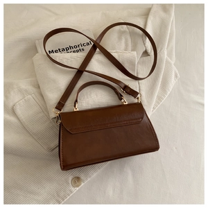 Vue détaillée d'un sac à main vintage en similicuir marron foncé avec boucles dorées
