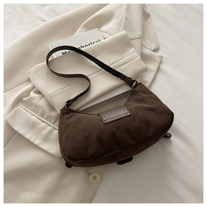 Détail du sac hobo en daim marron vintage sur un fond de blazer beige chic