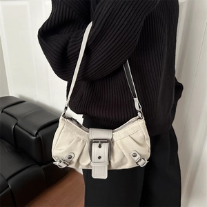 Sac à bandoulière plissé blanc cassé avec boucle vintage sur une tenue noire élégante
