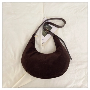 Macro view of dark brown frosted suede texture and leather strap on a moon-shaped bag