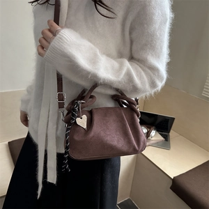 Braune Wildleder-Cloud-Bag mit Herzanhänger und Knotengriff an einem Modemodell