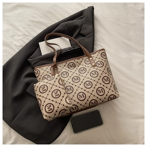 Flat lay of cream monogram tote bag set with matching pouch and dark brown leather trim