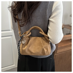 Détail du sac plissé marron avec pendentif en cœur et bandoulière en corde tissée