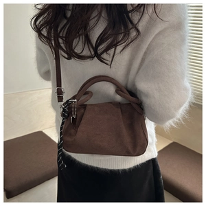 Détail du sac bandoulière vintage en daim marron avec breloque cœur et nœud tissé