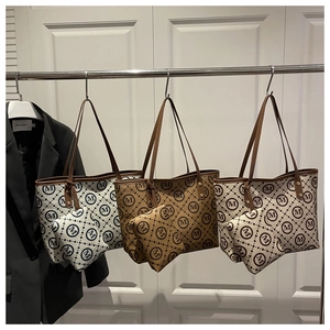 Three monogram canvas tote bags with leather straps hanging on a metal rack in detail