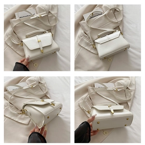 Detailoverzicht van de witte handtas met gouden gespen en verstelbare schouderriem