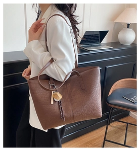 Brown crocodile pattern tote bag with bear charm shown in a professional office setting