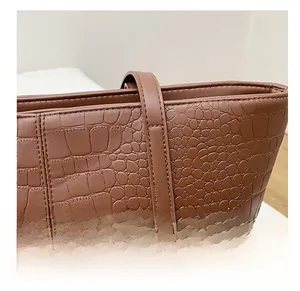 Close-up of tight stitching on dark brown crocodile embossed leather tote bag