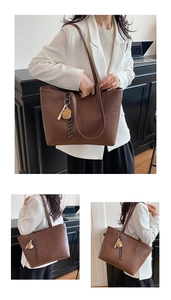 Close-up of brown crocodile pattern tote bag with a cute bear charm in office setting
