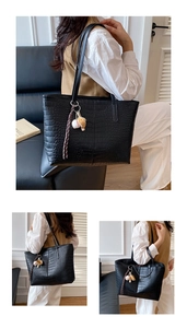 Close-up of black crocodile pattern tote bag with creative hanging charm accessories