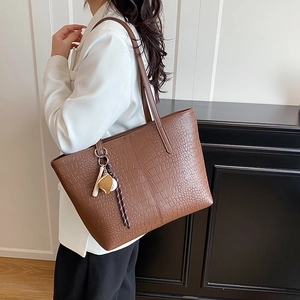 Brown crocodile pattern large tote bag with baseball charm on model in white blazer