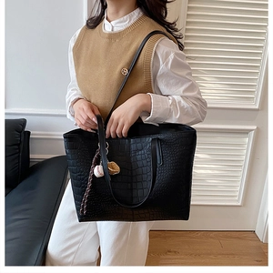 Close-up of black crocodile embossed tote bag with baseball glove charm and spacious interior