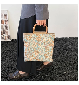Detail of floral tapestry tote bag featuring vintage bamboo handles and woven texture
