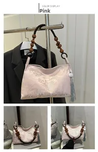 Detailed view of pink jacquard fabric with traditional patterns and dark wooden bead strap