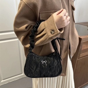Sac sous le bras plissé noir minimaliste avec nœud argenté porté par un modèle