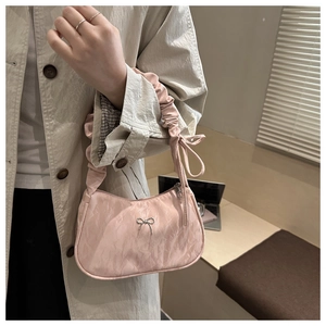 Détail du sac bandoulière en satin rose avec nœud argenté et anse à plis élégante