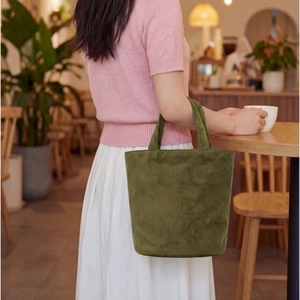 Dettaglio della borsa tote verde scuro in pelle scamosciata con trama morbida e design squadrato