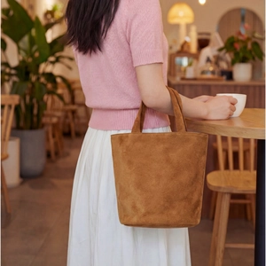 Borsa tote in camoscio marrone in un caffè accogliente, focus sulla consistenza morbida