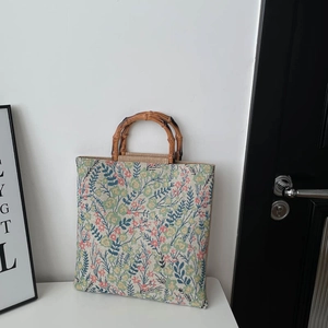 Floral tapestry tote bag with bamboo handles in a minimalist home interior setting