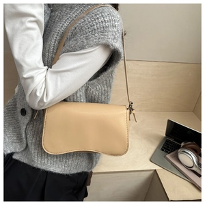 Detail of light beige matte leather shoulder bag with sleek curved base and adjustable strap