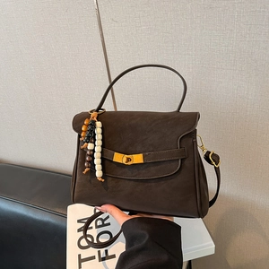Close-up of vintage matte brown satchel with gold twist lock and beaded charm accessory
