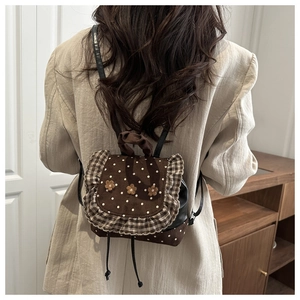 Detail of a brown polka dot mini backpack with floral accents and ruffled edges