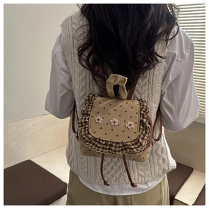 Detail view of mini backpack with white daisy embroidery and polka dot canvas texture