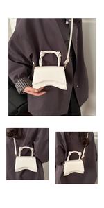 Detailed view of white faux leather bag with curved base and twisted handle style