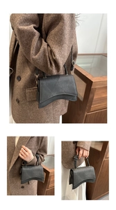 Detail of grey crossbody bag with knotted handle and unique curved base design