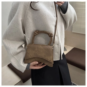 Close-up of brown suede mini square bag featuring unique knotted handle and curved flap