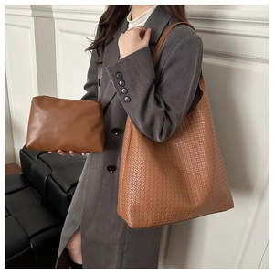 Brown woven tote bag with matching pouch shown on a model in a grey wool coat