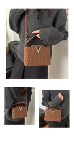 Detail of leopard print handbag featuring a gold V-shaped buckle and adjustable strap